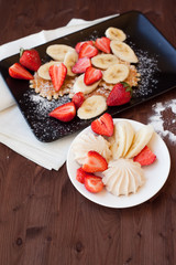 Waffles with fresh strawberries and bananas on rustic wooden background. Top view