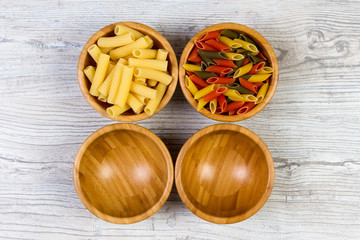 Various combinations of pasta on wooden background, burlap bags, bamboo bowls. diet and nutritional concept.