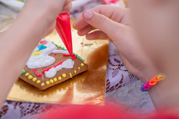 child draws on gingerbread with glaze