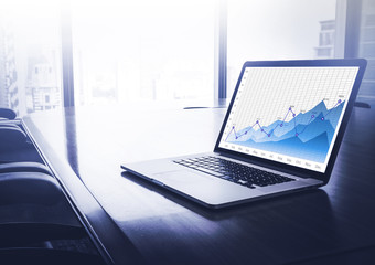 Business financial graph chart on laptop in modern blue conferen