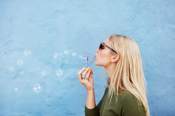 Young beautiful woman blowing soap bubbles