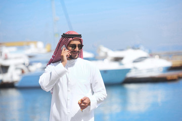 Arabian man talking on the cell phone at the yacht harbor