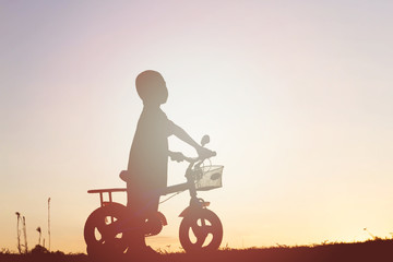 Obraz na płótnie Canvas little boy bike silhouette