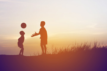 children playing ball on meadow, sunset, summertime