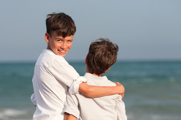 Portrait of happy brothers in white shirts on background of sea