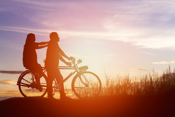 Fototapeta premium silhouette of couple driving bike happy time sunset