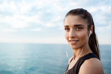 Portrait of young beautiful sportive girl at sunrise over seaside. 