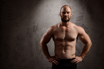 Fototapeta premium Portrait of young powerful sportsman over dark background.
