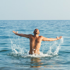 Handsome muscular guy jumping from water
