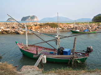 Old fishing boat is docked on the background of the shore rocks and grass