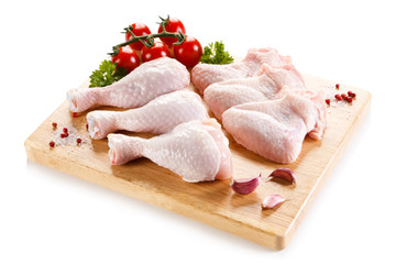 Raw chicken wings and drumsticks on cutting board on white background 