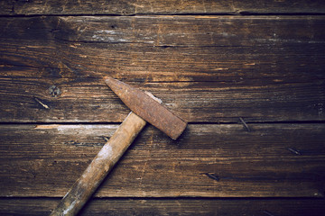 Old steel hammer with wooden handle on the wooden boards background