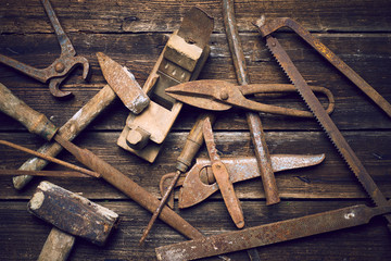 Grungy old rusted tools on a wooden background (processing cross-process)