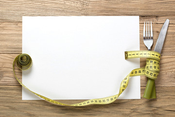 sheet of white paper on the wooden desk with knife and fork wrap