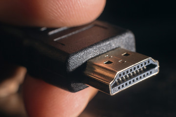 Hand holding black HDMI cable. Man's hand holds a HDMI Connector. Closeup HDMI cable.
