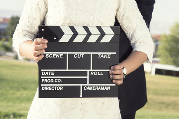 Happy beautiful bride and groom, woman holds clapper board, cinema board