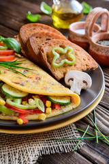  Omelet with pepper, tomato, corn, green onion, cucumber, mushrooms and fried bread on a wooden background