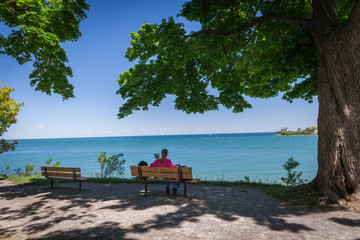 Young beautiful woman sitting on a bench on the lake shore and w