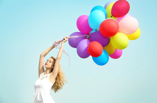 Happy woman with colorful balloons on blue sky background