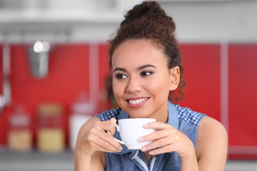 African American woman with a cup of coffee in kitchen