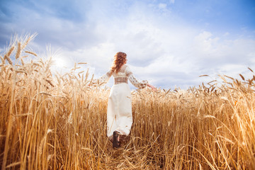 Pretty woman dressed in embroidered blouse in wheat field © favorestudio