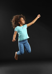 Happy African girl jumping on black background