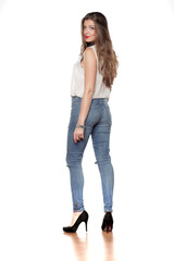 back view of beautiful young woman in jeans and a shirt on a white background