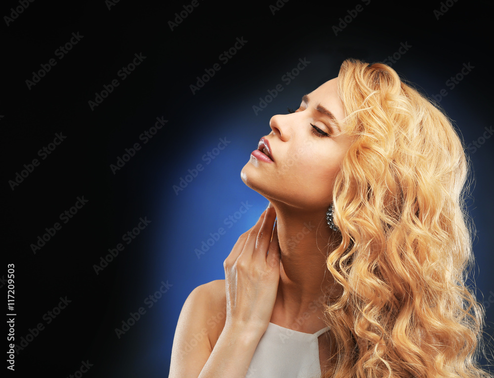 Wall mural Portrait of young woman with blonde hair on dark background