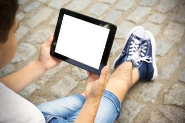 Young man with gadget on block stones background