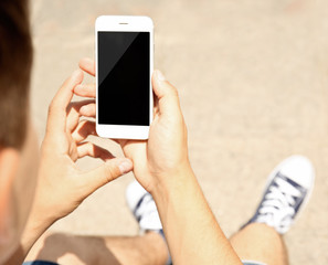 Young man with gadget sitting on stairs