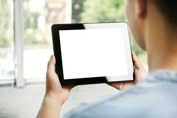 Young man with gadget on window background