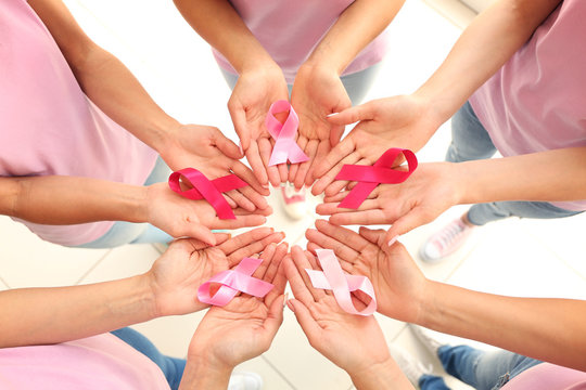 Female Hands Holding Pink Ribbons. Breast Cancer Concept