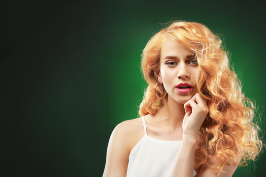 Portrait of young woman with blonde hair on dark green background