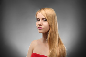 Young blonde woman with long hair on color background