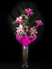 Bouquet of orchids stands in a glass vase on a black background