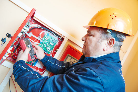 electrician measuring electric circuit with multimeter in fuse box