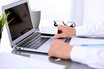 Close up of business woman hands using credit card and laptop computer