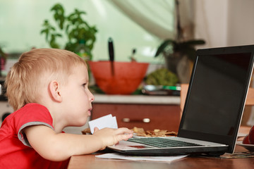 Fototapeta na wymiar Little boy with laptop on table in home.