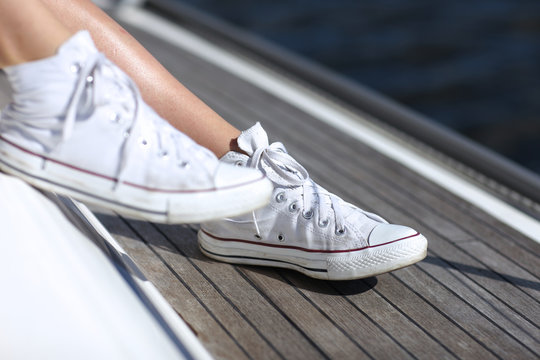 Woman Feet With Sneakers On Ship Deck