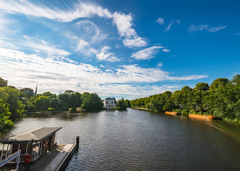 Alster Lake in Hamburg Germany on a summer day. Beautiful view at old building in city park near famous Krugkoppelbrücke, bridge and ferry station, image for travel business