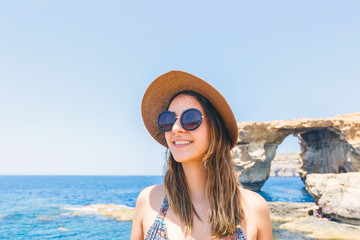 Young woman with hat on the rocky beach on summer vacation in Malta