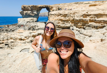 happy female friends taking selfie picture together on the rocky beach in Malta
