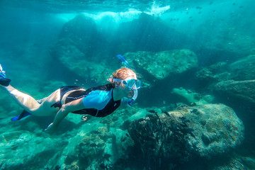 Young lady snorkeling over coral reefs in a tropical sea. Similan Islands in Thailand, one of the...