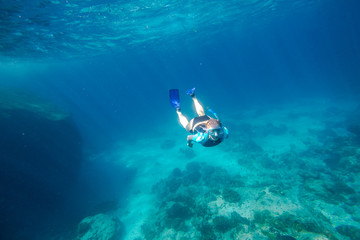 Young female apnea swims in deep waters of the popular Similan Islands in Thailand, Andaman Sea.