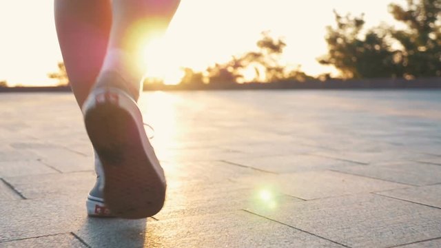 Close up shot of feminine feets walking in park during sunset or sunrise