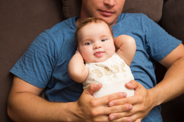 Image of young dad with cute little daughter in his arms. Father and newborn baby child indoor.


