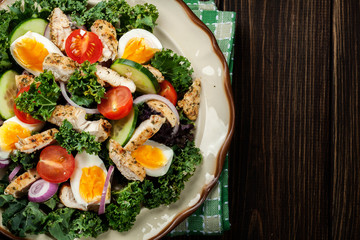 Fresh salad with chicken, tomatoes, eggs and lettuce on plate