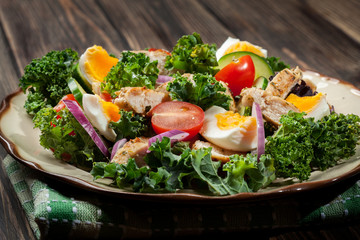 Fresh salad with chicken, tomatoes, eggs and lettuce on plate