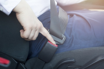 Female hand unfastening seat belt in car