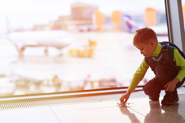 little boy playing with toy plane in the airport